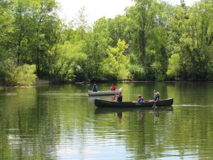 canoes on the river with green trees surrounding the water