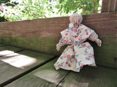 ragdoll propped up on wood bench outdoors
